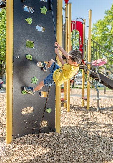 Jouer au parc aide le cerveau des enfants pour l'école article par Jambette - garçon descendant un mur d'escalade au parc